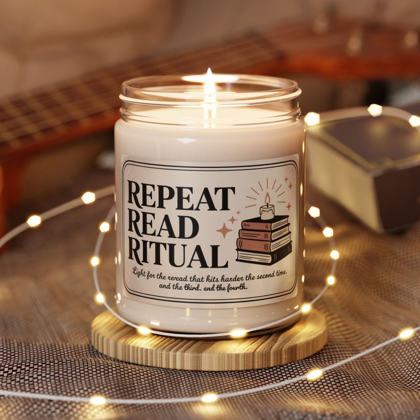 Candle in a jar with a label reading 'Repeat Read Ritual' on a wooden coaster, surrounded by string lights and a guitar in the background.