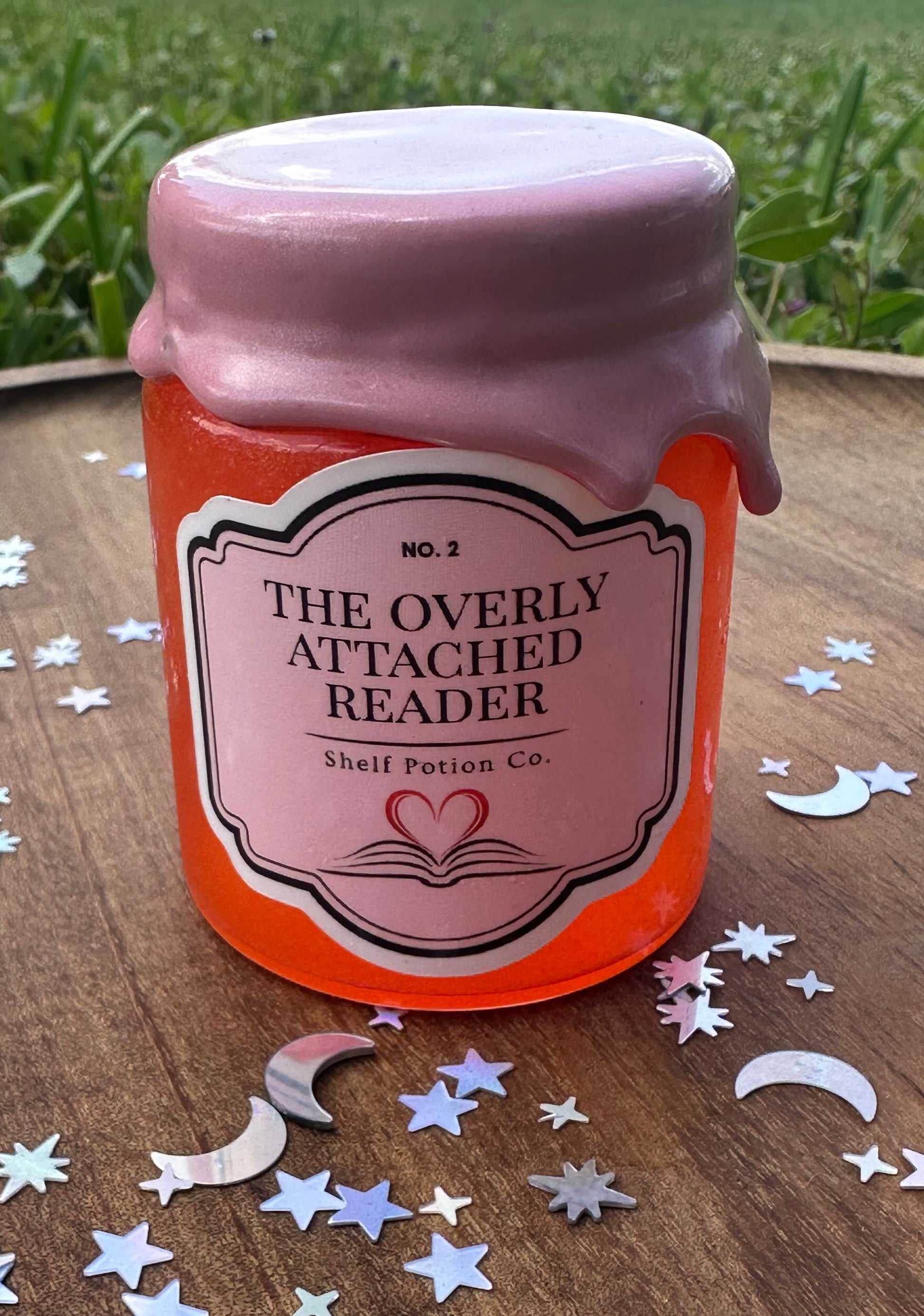 Jar labeled 'The Overly Attached Reader' with decorative stars and moons on a wooden surface.