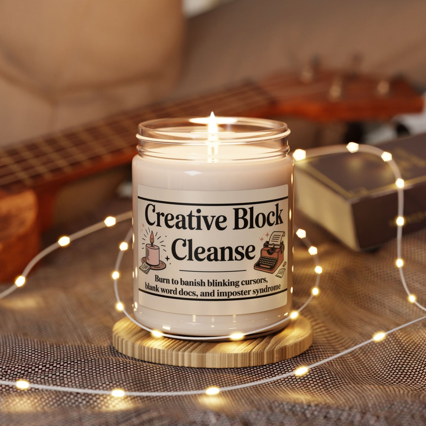 Candle labeled 'Creative Block Cleanse' with a guitar and string lights in the background