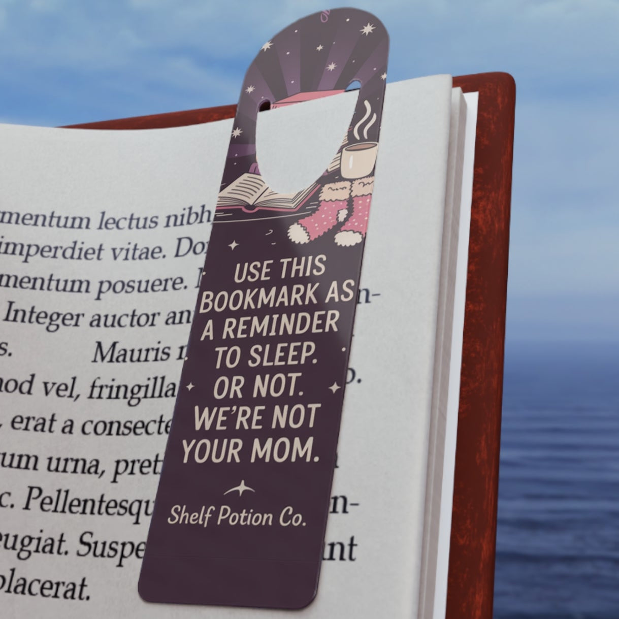 Open book with a bookmark featuring text, against a scenic background of water and sky.